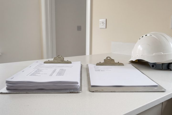 Two reports and a hard hat on a kitchen worktop