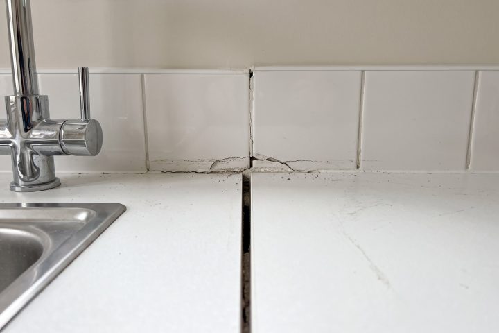 Open kitchen worktop joint with cracked grout along the splashback