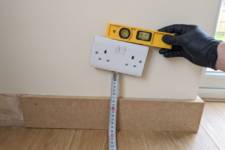 Plug socket out of level with a spirit level and tape measure against it