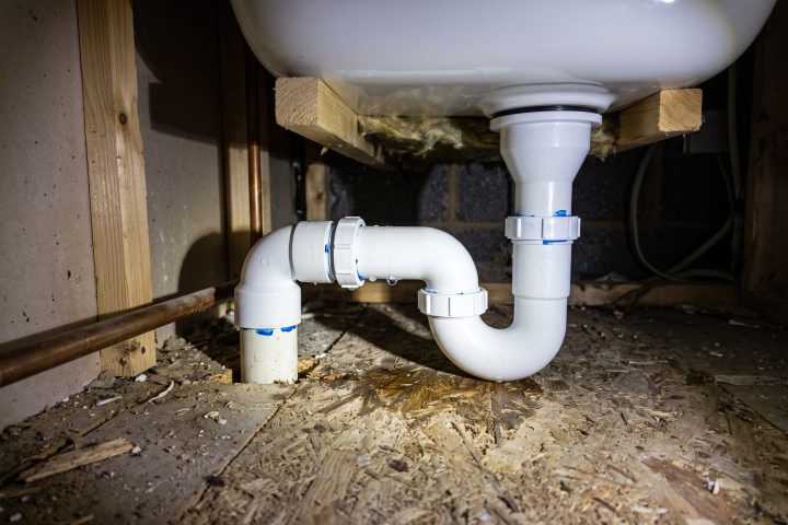 Waste trap under a bath with a bead of water on the joint
